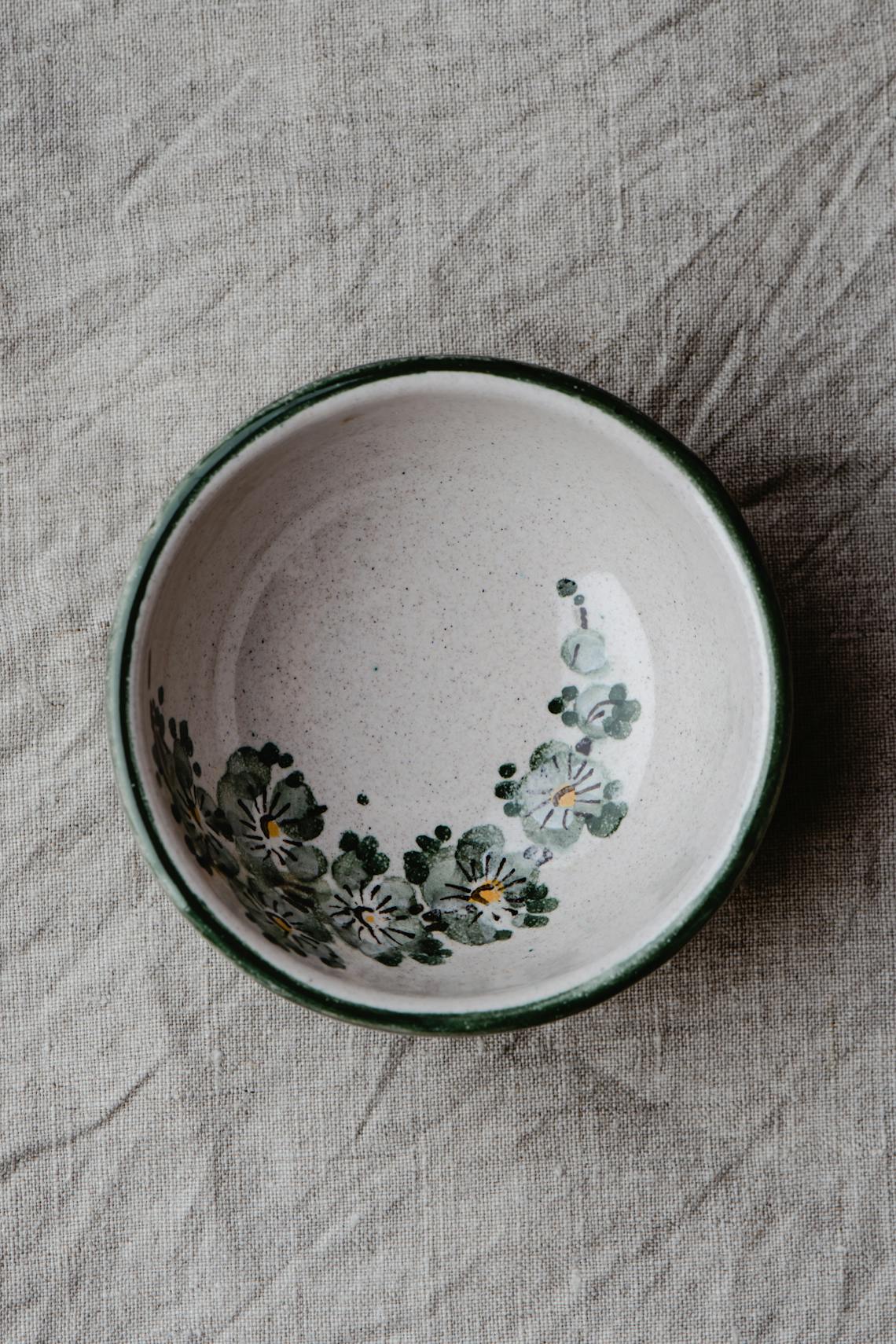 Aerial view of a decorative ceramic bowl with floral patterns on a textured fabric.