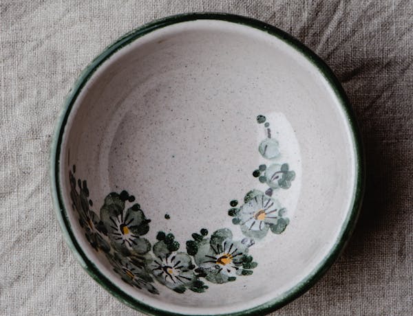 Aerial view of a decorative ceramic bowl with floral patterns on a textured fabric.