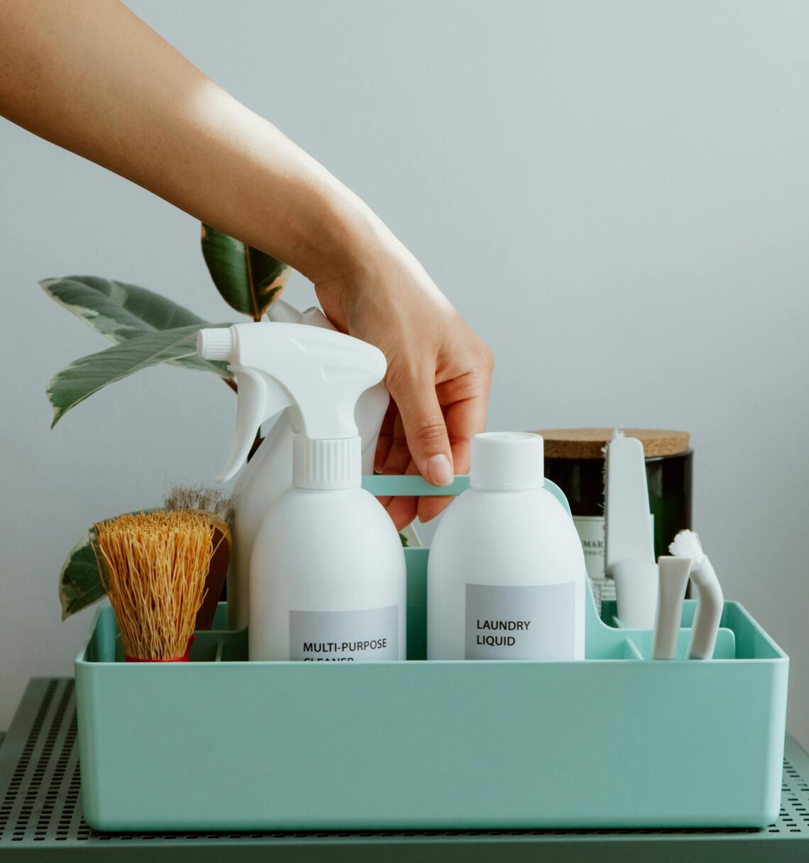 Hand arranging cleaning products in a tidy organizer, promoting cleanliness and order.