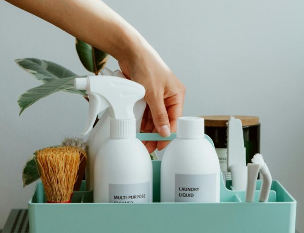 Hand arranging cleaning products in a tidy organizer, promoting cleanliness and order.